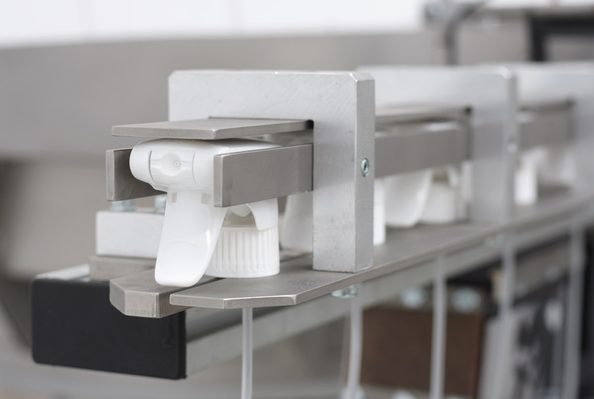 Alimentador industrial vibratorio para el posicionamiento automatizado de triggers, del sector de envases vista detalle salida cinta